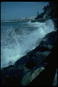 005049 Waves Breaking On Rocks With City, Jetty A4 Photo Print