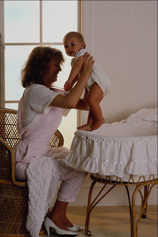 635088 Mother Lifting Baby From Crib A4 Photo Print
