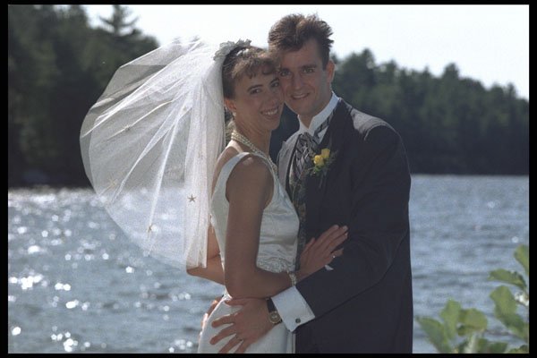 702090 Bride And Groom Embracing In Front Of Water Setting A4 Photo Print