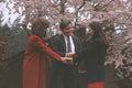 719002 Two Women And A Man Shaking Hands In Front Of Tree A4 Photo Print