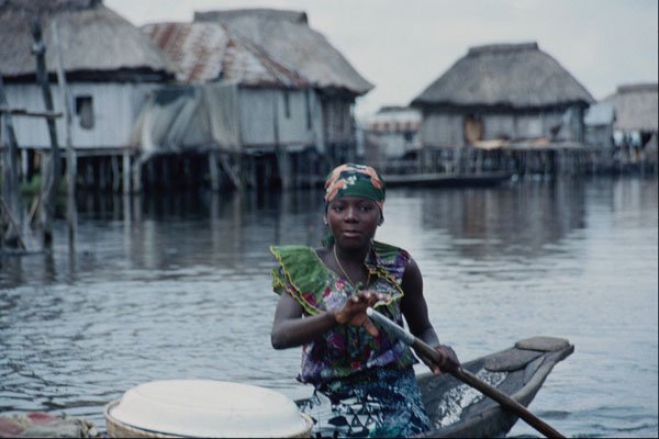 783034 Woman Rowing Around From House To House Selling Goods A4 Photo Print